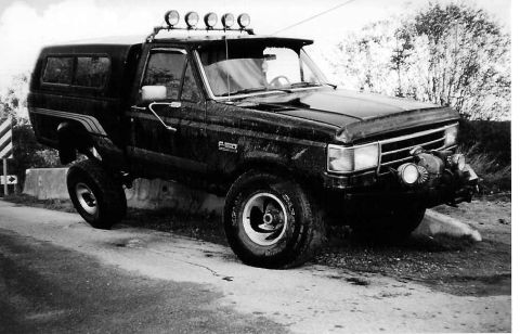 1990 Ford F-150 - This lifted Ford Bronco is equipped with a camper shell and auxiliary lights for off-road use.