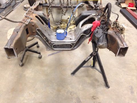 1993 Ford Bronco - A vehicle frame is suspended by chains and supported by stands, with engine components attached.