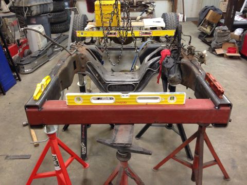 1993 Ford Bronco - Vehicle frame assembly being worked on, supported by jack stands and measured with levels.