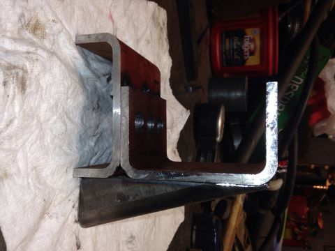 1993 Ford Bronco - A metal bracket with visible bolt holes is shown in a workshop setting, alongside various automotive fluids and tools.
