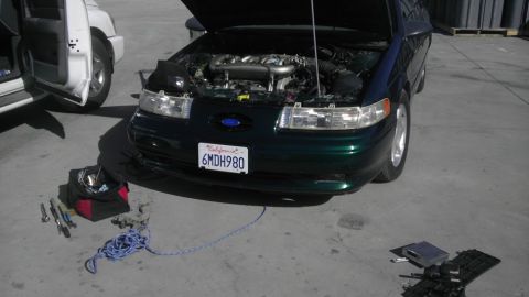 1993 Ford Taurus - A dark green 1993 Ford Taurus is parked with its hood open, revealing the engine compartment.
