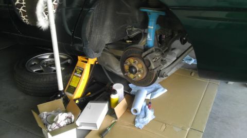 1993 Ford Taurus - The rear brake system of a vehicle is shown with a jack and various tools laid out on the ground.