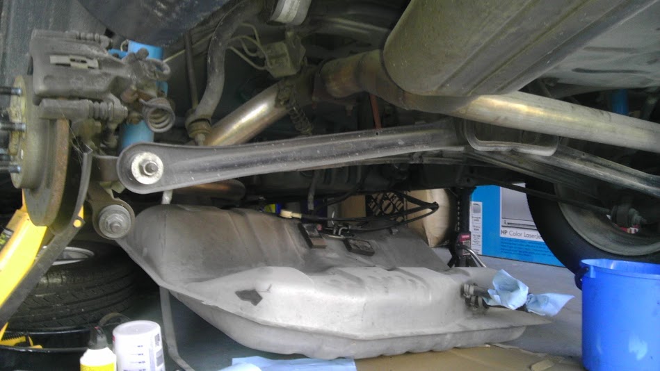 Undercarriage of a car with fuel tank removed, showing suspension and exhaust system