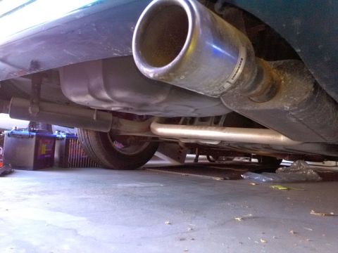1993 Ford Taurus - Underside view shows the exhaust system and fuel tank of a vehicle, with a car battery in the background.
