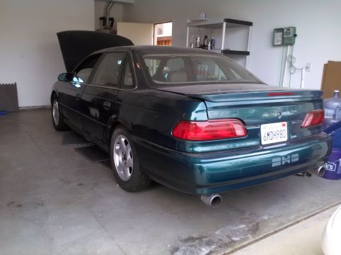1993 Ford Taurus - Rear view of a 1993 Ford Taurus in a garage. The hood is open, and the license plate is visible.