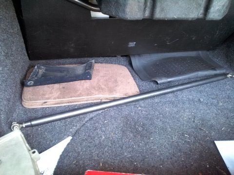 1993 Ford Taurus - The trunk of a vehicle contains a metal bar, floor mats, and a black plastic component.