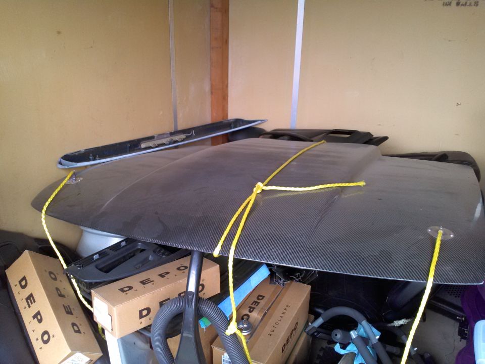 carbon fiber hood tied down with yellow rope, boxes labeled DEPO in background