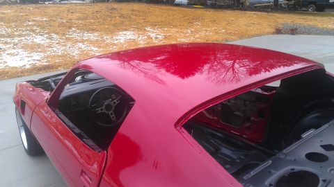 1972 Pontiac Trans Am - The red car's roof reflects trees and sky, showing its interior and a partial view of the front.