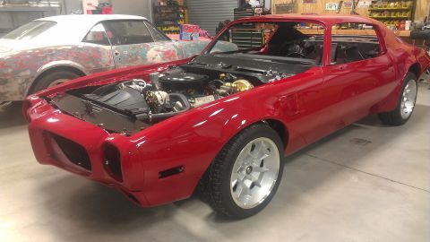 1972 Pontiac Trans Am - Red Pontiac Firebird in a workshop, likely undergoing restoration work.