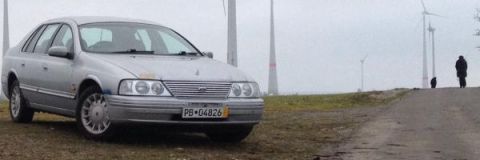 1999 Ford Fairlane - A silver 1999 Ford Fairlane sedan is parked outdoors with wind turbines in the background.