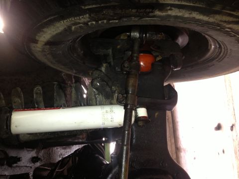 1995 Ford Bronco - Underside view of a vehicle's suspension system, showing the steering linkage and a white shock absorber.