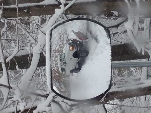 1994 Ford Bronco - A reflection in a snow-covered side mirror reveals a dark vehicle in a winter scene.