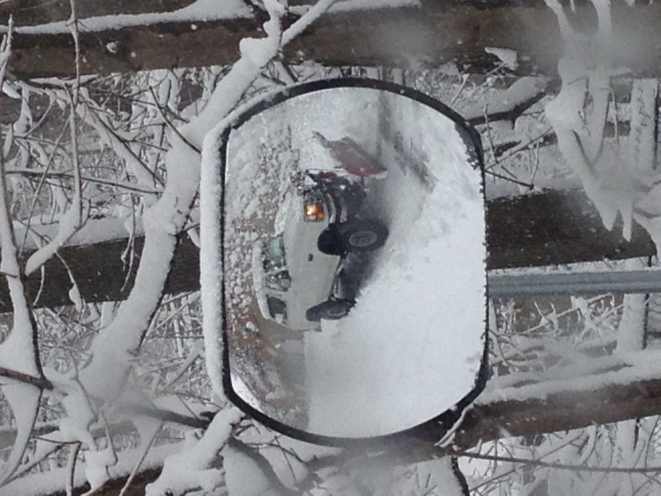 Convex mirror reflecting a snow-covered pickup or SUV in a winter wooded setting