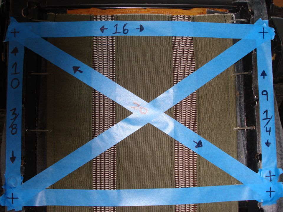 Car seat fabric with blue tape forming an X and rectangle, marked with measurements