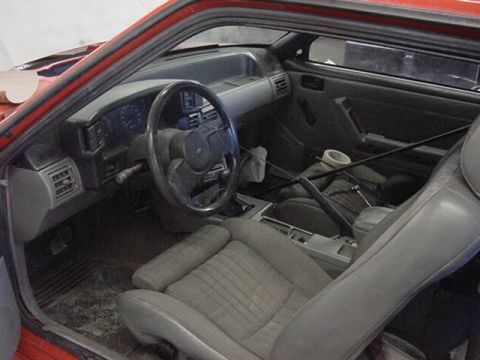 1990 Ford F-150 - Interior of a red car, likely a 1990s model, with gray cloth seats and dashboard visible.