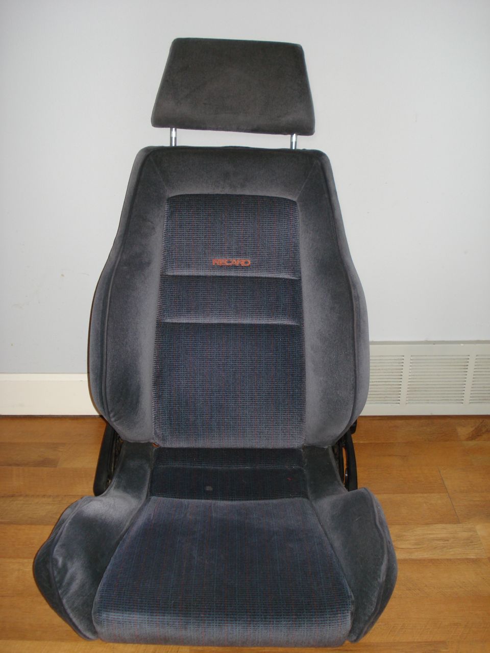 Dark gray fabric car seat with headrest and orange Recaro logo