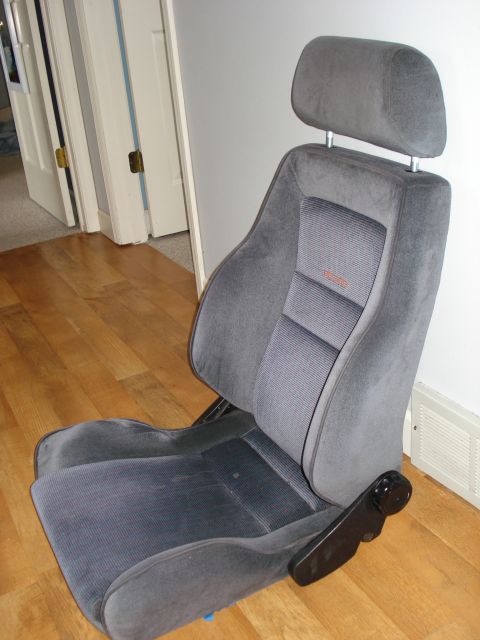 1972 Ford Pinto - A gray fabric car seat with a prominent orange 'RECARO' logo is shown indoors.
