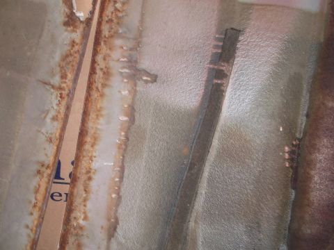 1967 Ford Mustang - Rust and water damage are visible on this interior car panel, with a piece of cardboard showing partial text.