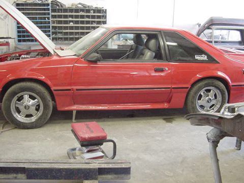 1990 Ford F-150 - A red coupe is parked in a garage with its hood up, revealing the engine bay.