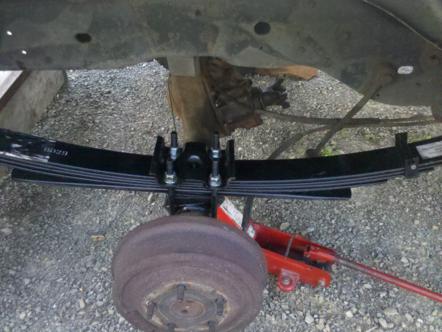 1982 Ford Bronco - Close-up view of a vehicle's rear suspension component, a leaf spring, and brake drum.