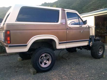 1982 Ford Bronco - This two-tone SUV appears to be undergoing significant modifications, with its front end completely disassembled.