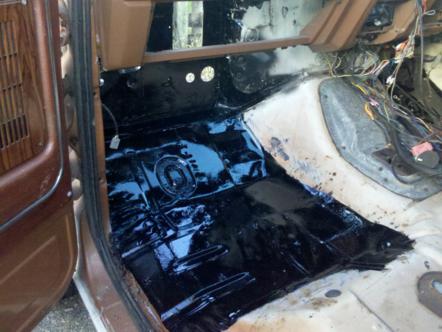 1982 Ford Bronco - The interior of a vehicle shows a freshly painted black floor and exposed wiring near the passenger seat.