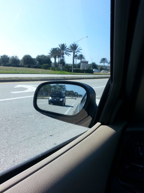 1992 Ford Bronco - A black SUV is visible in the side mirror of a vehicle driving on a road.