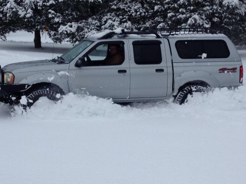 2003 Nissan Frontier - A silver pickup truck navigates through a snowy landscape, demonstrating its capability in winter conditions.