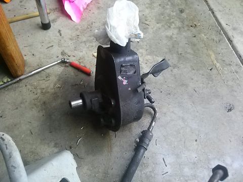 1996 Ford Bronco - A detached power steering pump is shown on a garage floor, possibly awaiting repair or replacement.