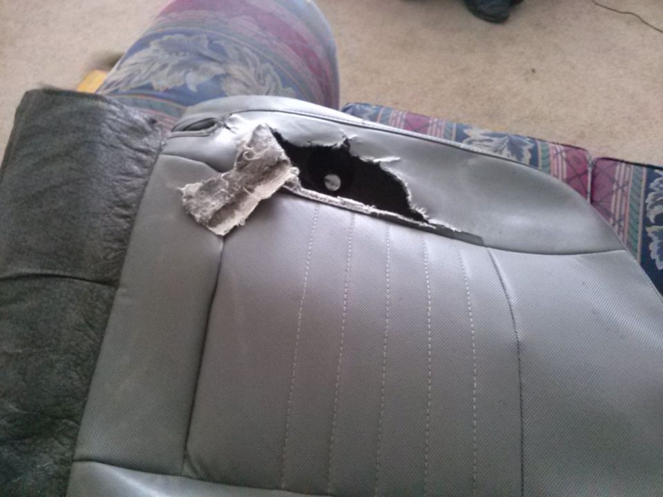 Torn gray car seat with stuffing showing through a large rip