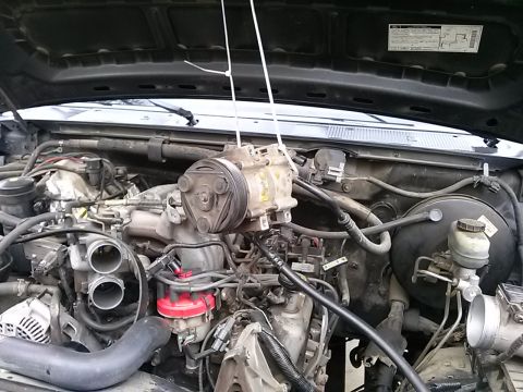 1996 Ford Bronco - The engine bay of a 1996 Ford Bronco shows the air conditioning compressor removed for service.