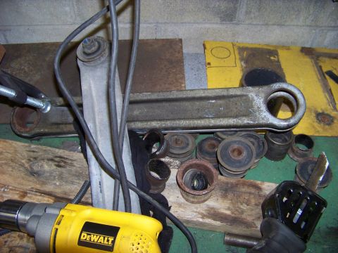 1999 Mercury Grand Marquis - A suspension control arm and several associated bushings are shown next to a yellow DeWalt drill.