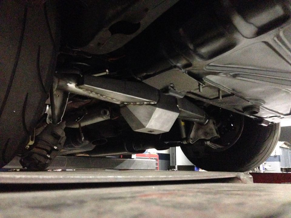 Underside view of a car showing custom metal fabrication on the rear axle and suspension components