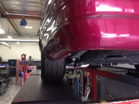 1992 Ford Crown Victoria - The underside of a vehicle is shown on a lift, focusing on the rear bumper and tire.