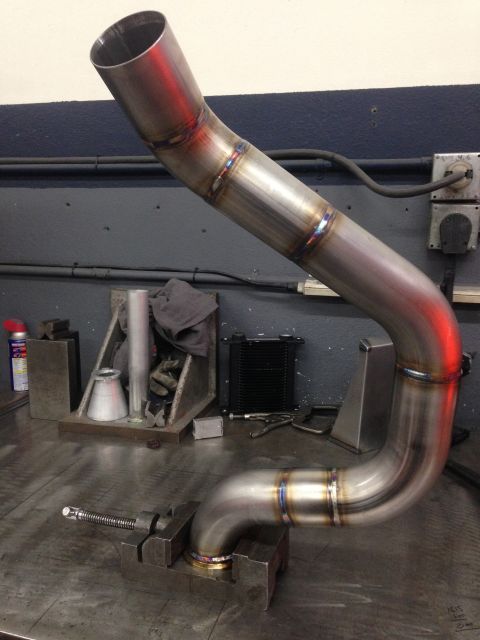 1992 Ford Crown Victoria - A custom exhaust pipe, fabricated from stainless steel, is held in a vise on a workbench.