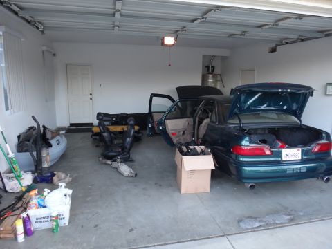 1993 Ford Taurus - A green sedan sits in a garage with its doors and trunk open, revealing interior parts and a license plate reading 6MDH980.