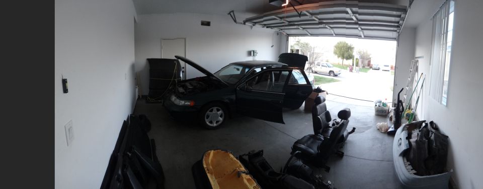 1993 Ford Taurus in a garage, hood and doors open, with interior parts on the floor