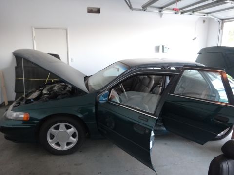 1993 Ford Taurus - A green 1993 Ford Taurus sedan is parked in a garage with its hood and doors open.