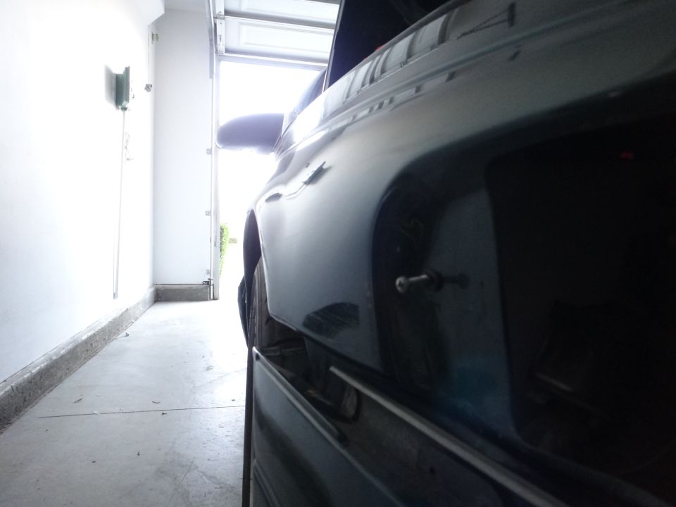 Car parked in a garage, side view showing rear quarter panel and door