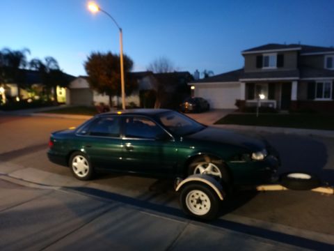 1993 Ford Taurus - A green 1993 Ford Taurus is parked on a trailer in a residential driveway at dusk.