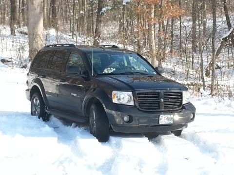 2007 Dodge Durango - A black SUV is stuck in deep snow in a wooded area, with its front tires partially buried.