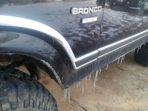 1986 Ford Bronco - Icicles hang from the side of a black Ford Bronco, indicating cold weather conditions.