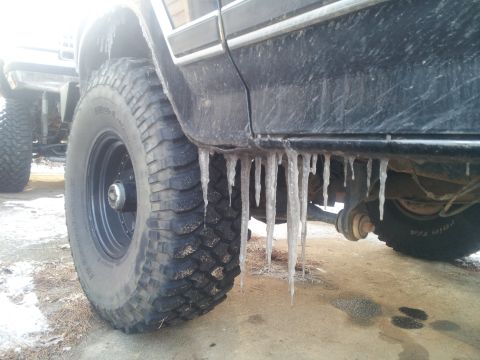 1986 Ford Bronco - Icicles hang from the side of a black SUV, with another vehicle visible in the background.