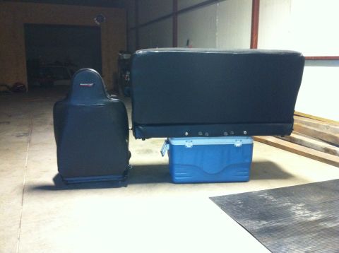 1982 Ford Bronco - A black car seat and a black bench seat are displayed on top of a blue cooler.