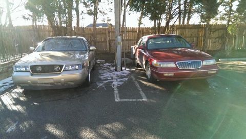 2000 Mercury Grand Marquis - Two Mercury Grand Marquis sedans are parked in a lot with snow on the ground.