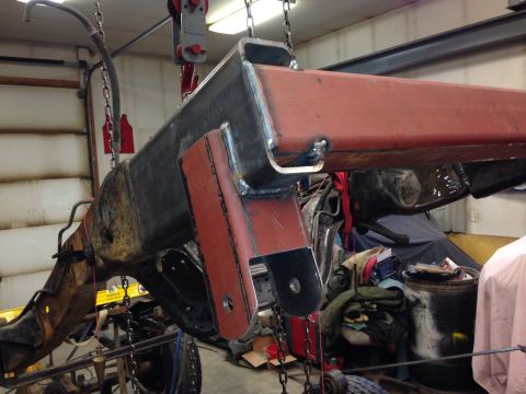 1993 Ford Bronco - A section of a vehicle frame, possibly undergoing repair or modification, is hoisted in a garage setting that appears to be a garage or wor…