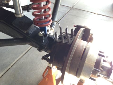 1987 Suzuki Samurai - The vehicle's suspension and brake components are visible, supported by jack stands.