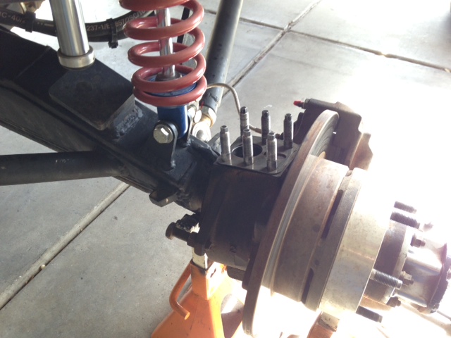 close-up of vehicle's front suspension and brake rotor assembly on jack stands
