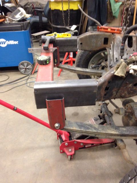 1993 Ford Bronco - A vehicle's frame is supported by a jack and undergoing repairs in a workshop setting.