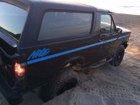 1992 Ford Bronco - This Ford Bronco appears to be stuck in the sand, with its rear tire partially submerged.